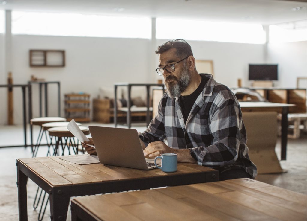 A person working on a laptop deciding which crypto to invest in.