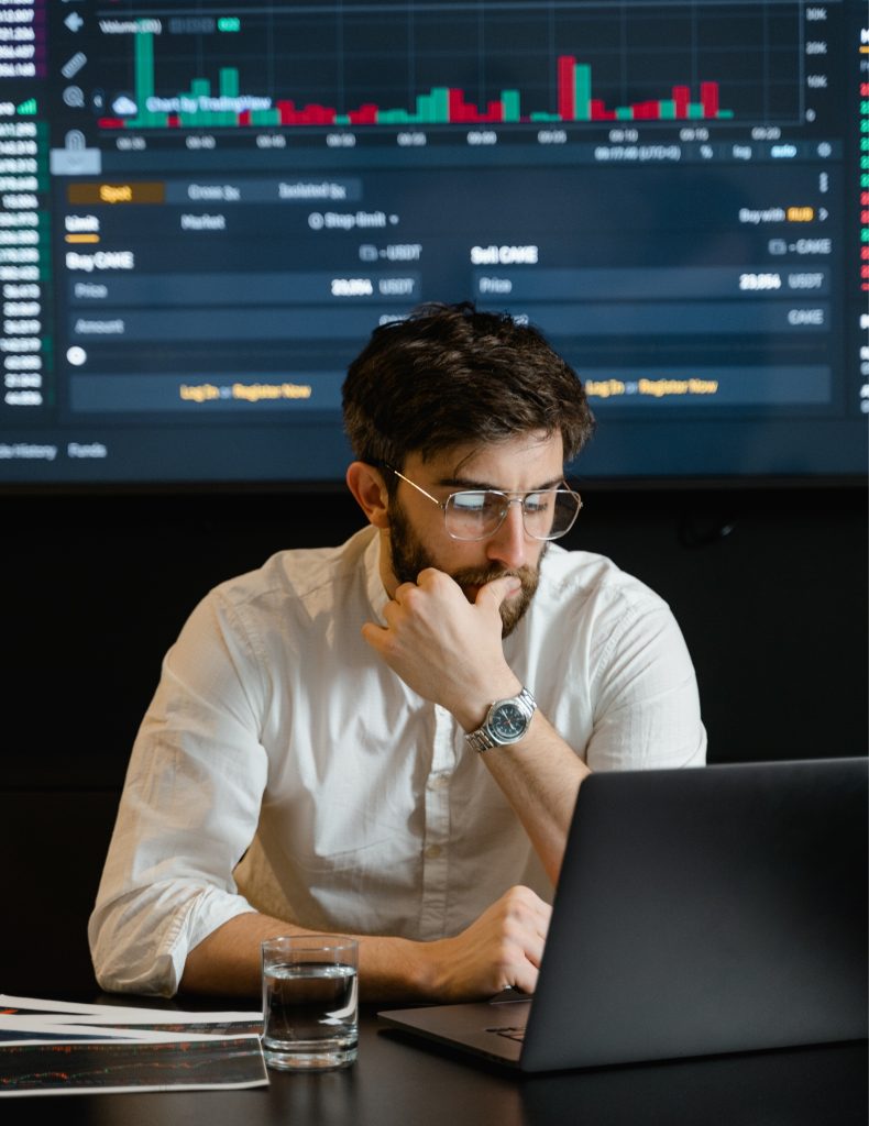 Image of a trader sitting at a table nd thinking about cryptocurrency trading strategies.