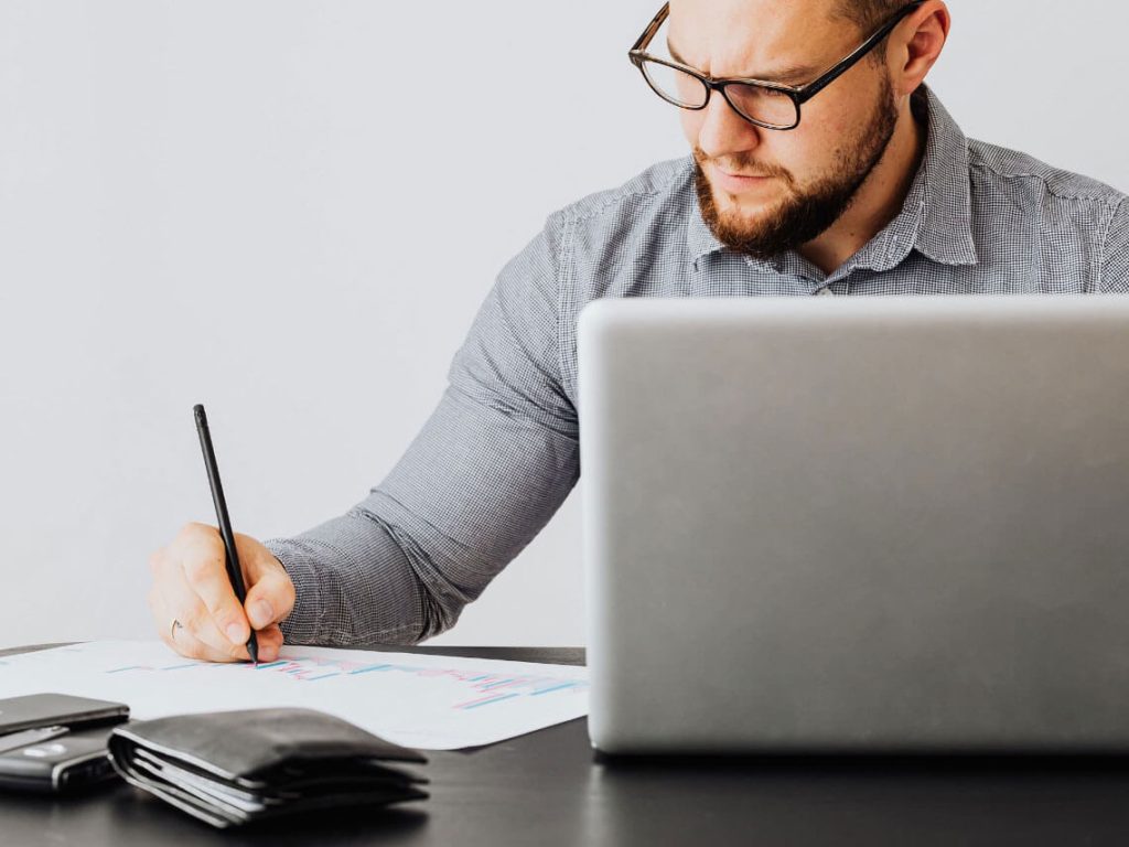 Person sitting at table and writing a note on a pad.